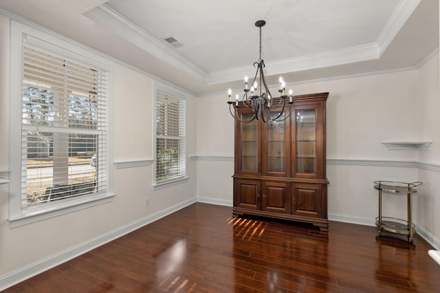 dining space with dark wood-type flooring, ornamental molding, and a raised ceiling