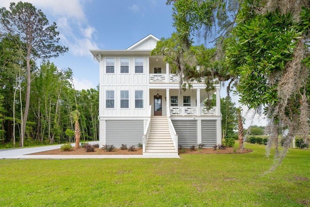 view of front facade with a balcony, board and batten siding, stairs, and a front lawn