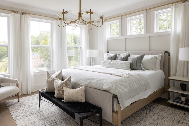 bedroom featuring wood finished floors, a chandelier, and crown molding