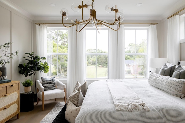 bedroom featuring wood finished floors, multiple windows, a notable chandelier, and ornamental molding