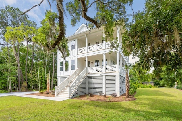 view of front of home with stairway, board and batten siding, covered porch, a front yard, and a balcony