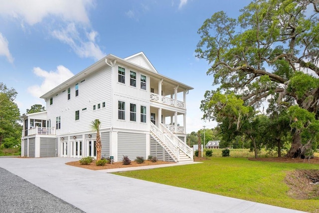 view of front of house featuring stairway, board and batten siding, covered porch, a front yard, and a balcony