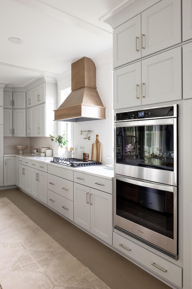 kitchen featuring stainless steel appliances, tasteful backsplash, light countertops, and custom range hood