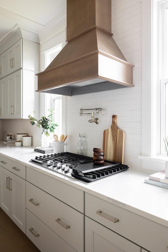 kitchen featuring custom exhaust hood, ornamental molding, tasteful backsplash, and stainless steel gas cooktop