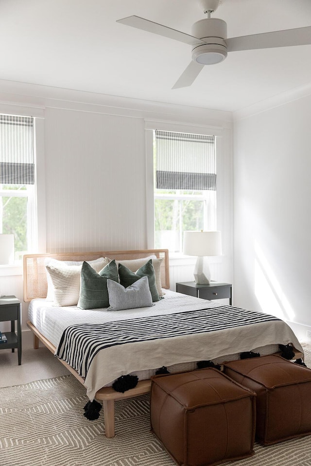 carpeted bedroom with multiple windows, ceiling fan, and ornamental molding