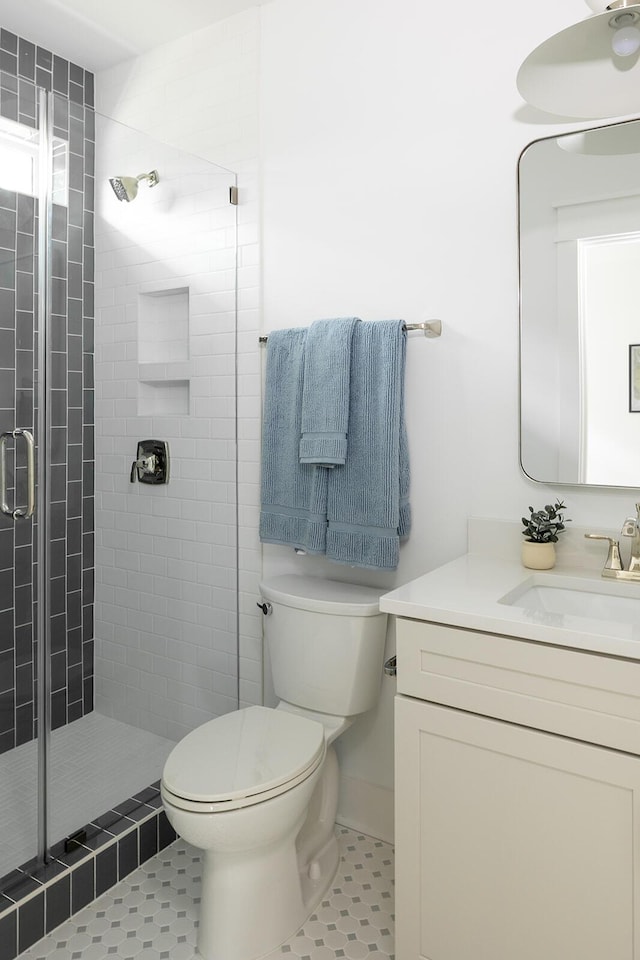 bathroom with vanity, tile patterned floors, toilet, and a stall shower