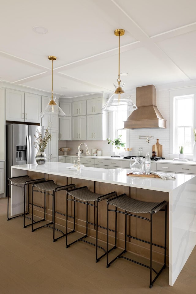 kitchen with a kitchen bar, custom range hood, decorative backsplash, a large island, and stainless steel appliances