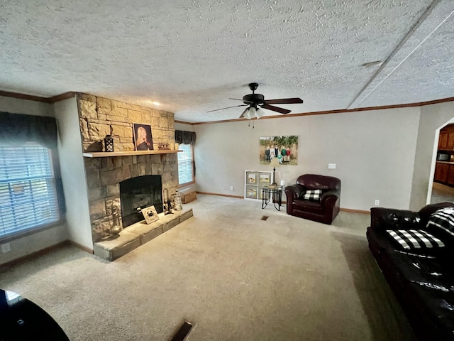 living room with a stone fireplace, carpet, ceiling fan, crown molding, and a textured ceiling