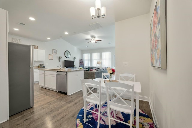 kitchen with white cabinetry, decorative light fixtures, a center island with sink, appliances with stainless steel finishes, and light hardwood / wood-style floors