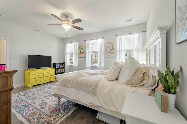 bedroom featuring ceiling fan, dark hardwood / wood-style floors, and multiple windows