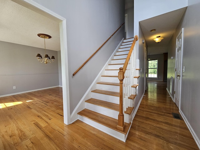 3564 Elliott Rd, Pinewood, SC 29125 - stairway featuring wood finished floors, a chandelier, a textured ceiling, and baseboards