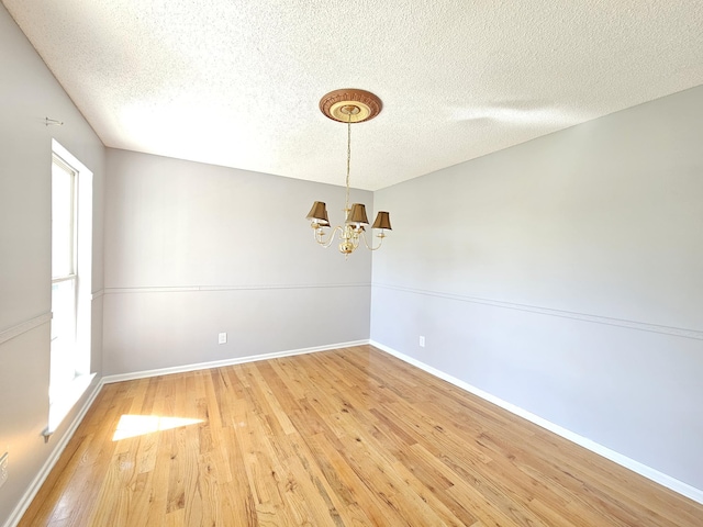 3564 Elliott Rd, Pinewood, SC 29125 - empty room with a chandelier, a textured ceiling, light wood finished floors, and baseboards