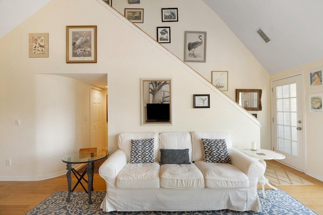 living room with high vaulted ceiling and light wood-type flooring