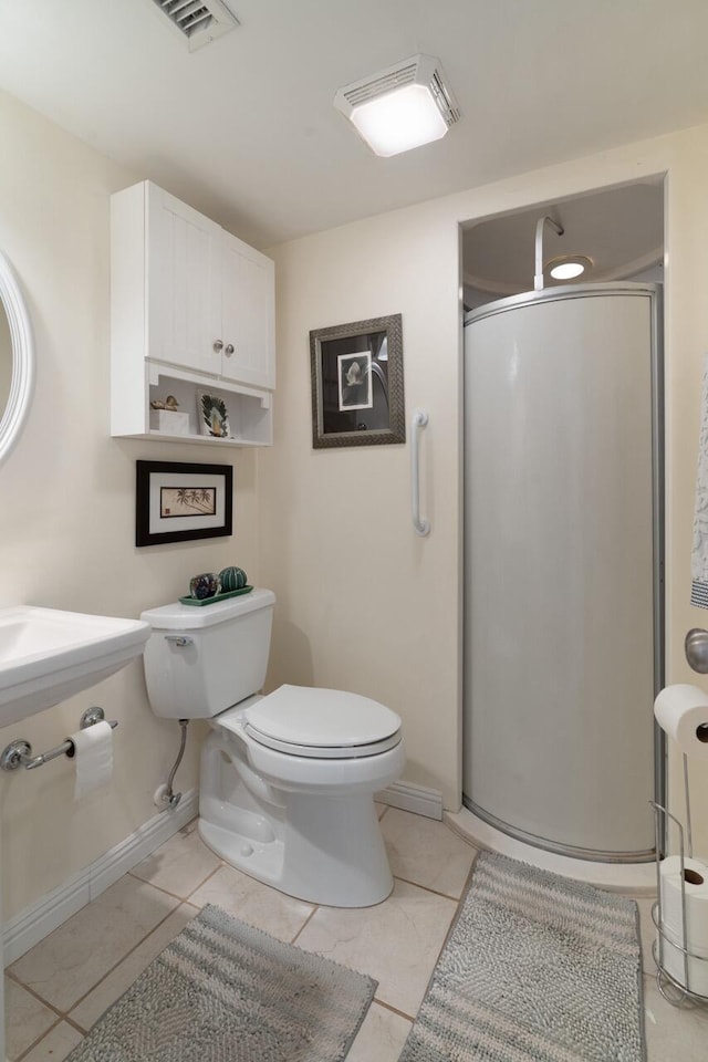 bathroom with toilet, tile patterned floors, and a shower with shower door