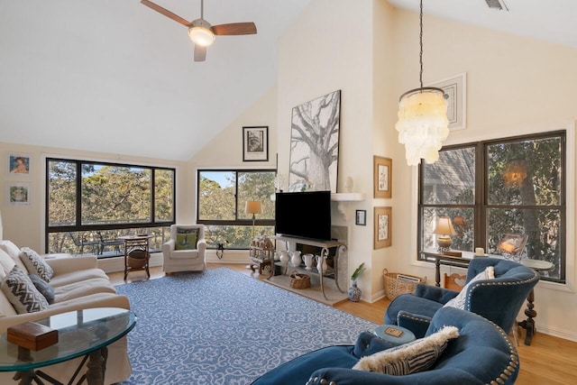 living room featuring hardwood / wood-style flooring, ceiling fan with notable chandelier, and high vaulted ceiling