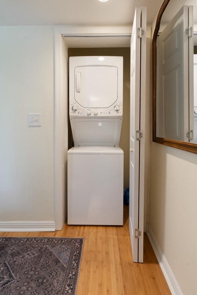 laundry room featuring stacked washer / dryer and light hardwood / wood-style floors