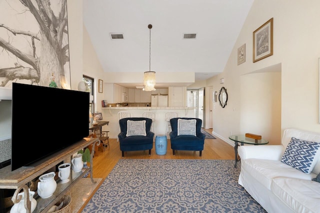 living room with high vaulted ceiling and light wood-type flooring