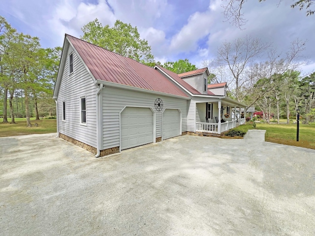 view of property exterior featuring covered porch, driveway, a garage, and metal roof