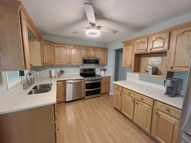 kitchen with ceiling fan, appliances with stainless steel finishes, light brown cabinets, a sink, and light wood-style floors