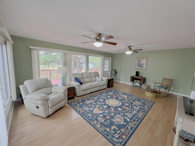 living room featuring baseboards, wood finished floors, ceiling fan, and a textured ceiling