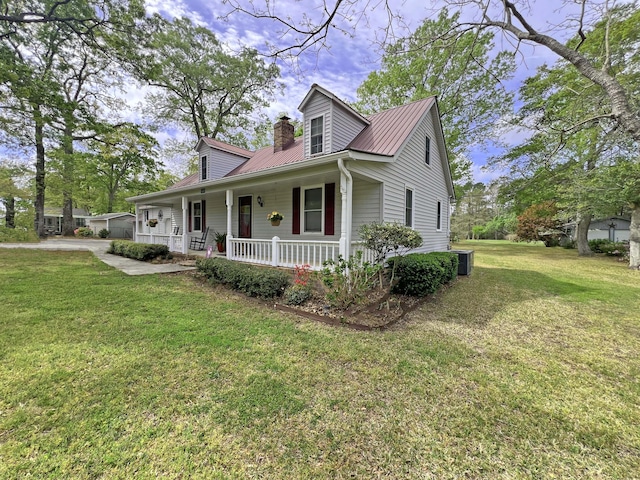 new england style home with metal roof, central AC unit, a chimney, a front yard, and covered porch