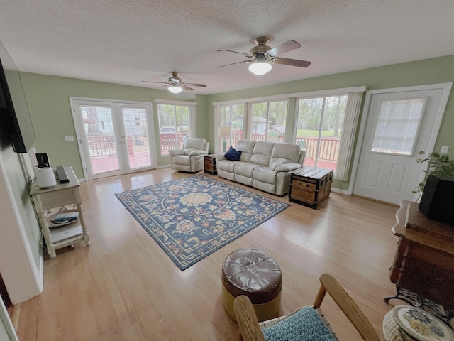 living area with a textured ceiling, ceiling fan, and light wood-type flooring