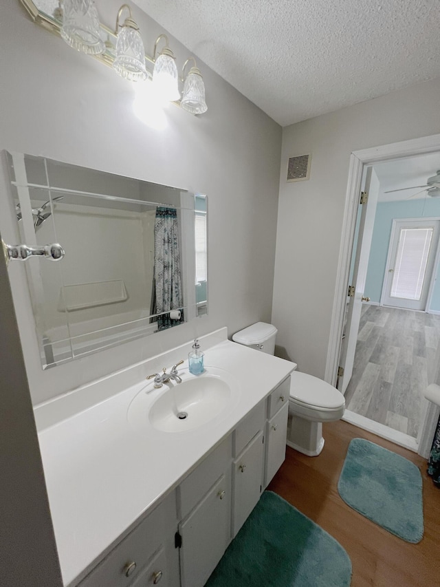 full bathroom featuring a textured ceiling, visible vents, vanity, and wood finished floors