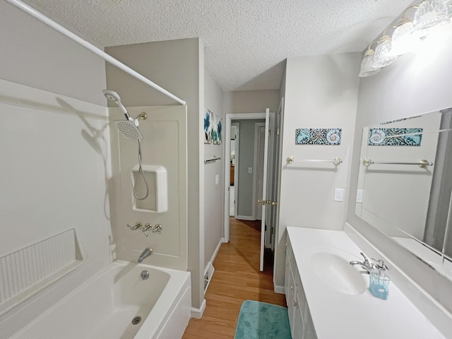 full bathroom with vanity, shower / tub combination, wood finished floors, a textured ceiling, and baseboards