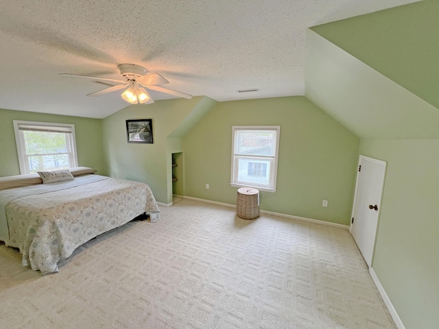 bedroom featuring a textured ceiling, multiple windows, lofted ceiling, and visible vents