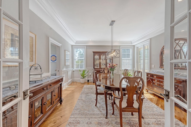 dining space featuring wainscoting, light wood-type flooring, and crown molding