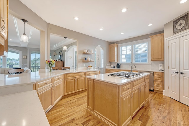 kitchen with stainless steel gas cooktop, light brown cabinets, arched walkways, and light countertops