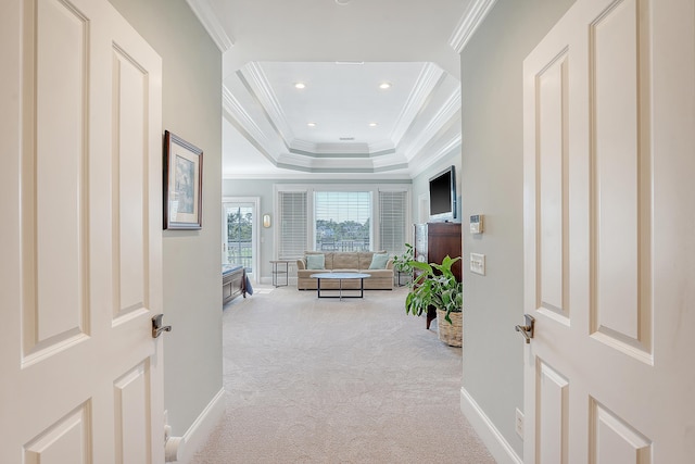 hallway with recessed lighting, a tray ceiling, crown molding, baseboards, and carpet flooring