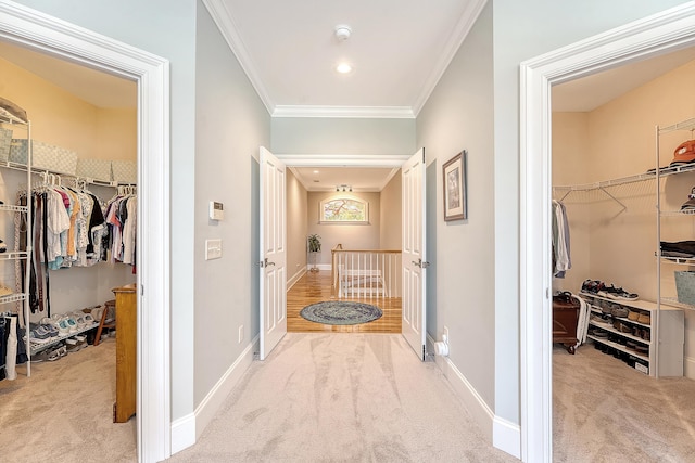 hall featuring baseboards, carpet floors, an upstairs landing, and ornamental molding