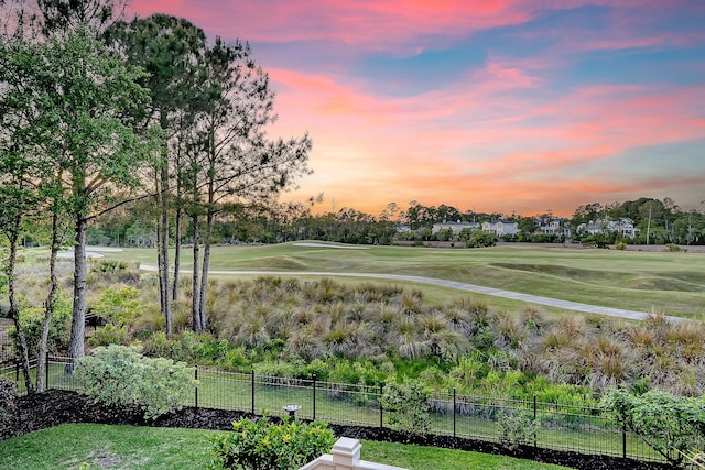 view of community featuring a yard, view of golf course, and fence