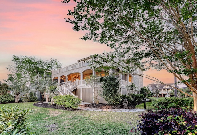 view of front of property with a balcony, covered porch, stairs, and a front yard