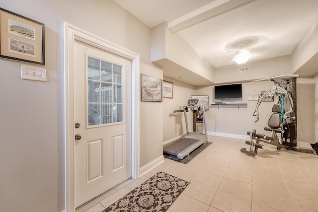 exercise room featuring baseboards, visible vents, and light tile patterned floors