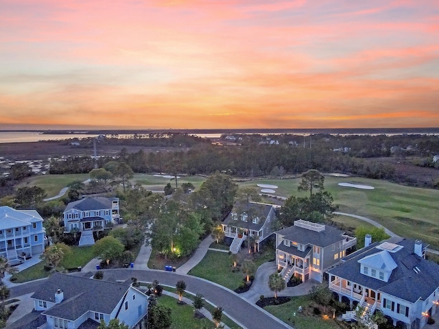 aerial view at dusk featuring a residential view, a water view, and view of golf course