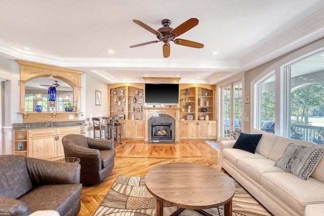 living area with a fireplace with flush hearth, ceiling fan, ornamental molding, and recessed lighting
