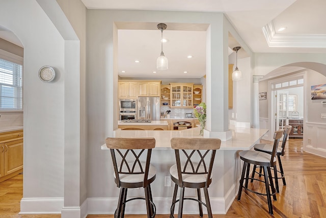 kitchen featuring decorative backsplash, glass insert cabinets, a breakfast bar area, arched walkways, and stainless steel appliances