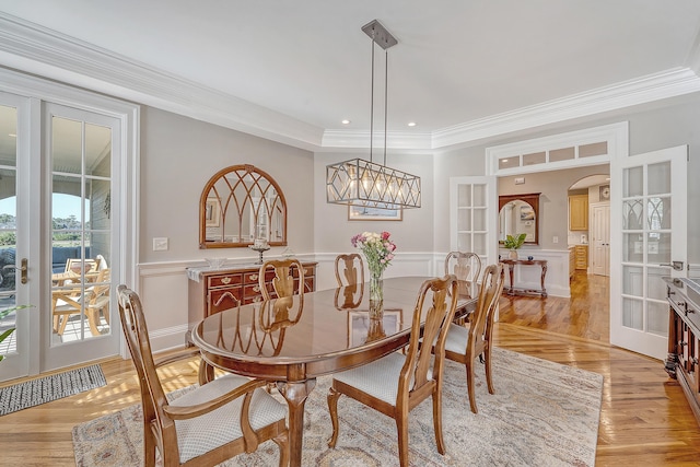 dining room featuring arched walkways, crown molding, and french doors