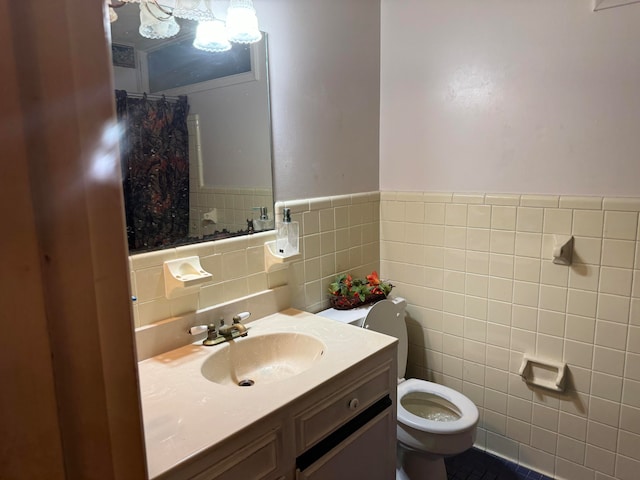 bathroom with walk in shower, tile walls, toilet, vanity, and tile patterned floors