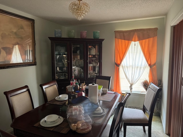 carpeted dining room with a notable chandelier and a textured ceiling