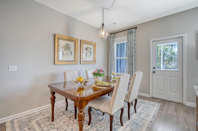 dining space featuring light wood-style floors, visible vents, a notable chandelier, and baseboards