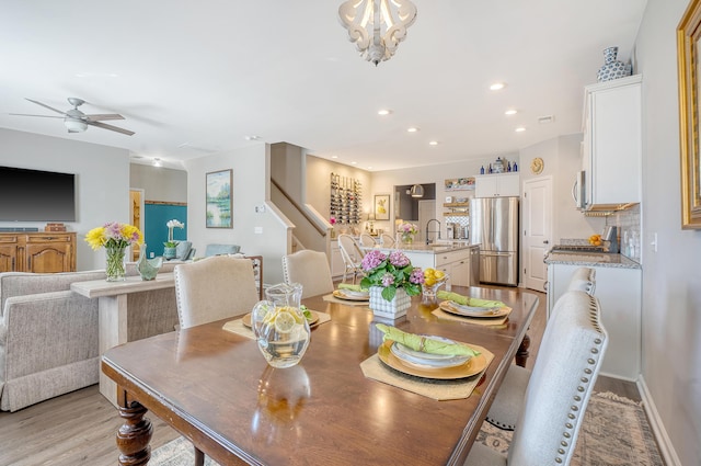 dining space featuring ceiling fan with notable chandelier, recessed lighting, light wood-style flooring, and stairs