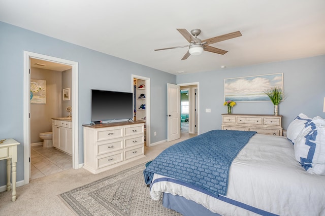 bedroom with light carpet, ceiling fan, baseboards, and ensuite bathroom