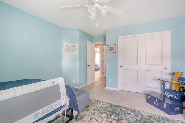 bedroom with baseboards, a closet, a ceiling fan, and light colored carpet