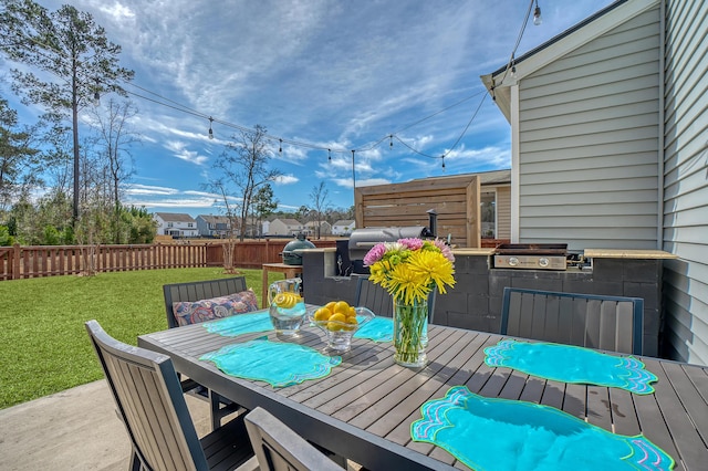 wooden terrace featuring a grill, fence, exterior kitchen, a yard, and outdoor dining space