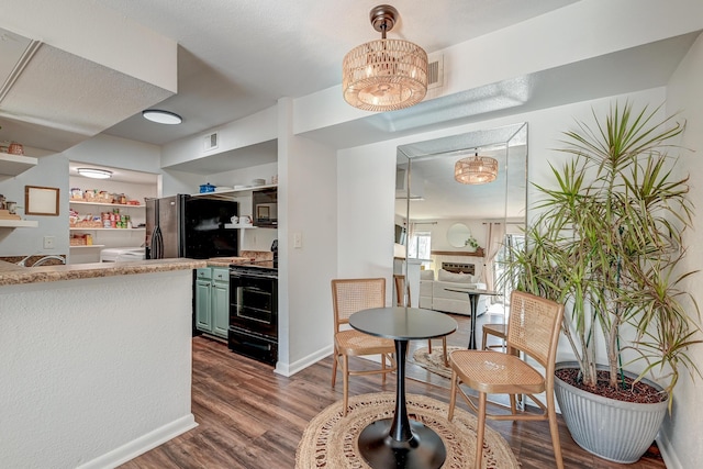 kitchen featuring green cabinets, black appliances, dark wood-style floors, and visible vents