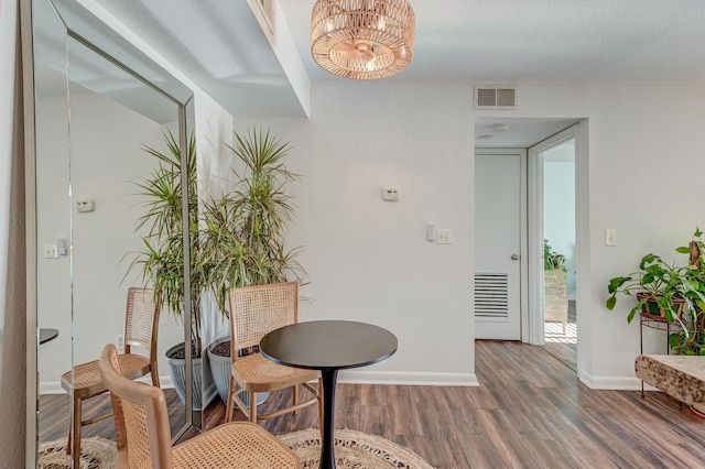 interior space with baseboards, visible vents, a chandelier, and wood finished floors