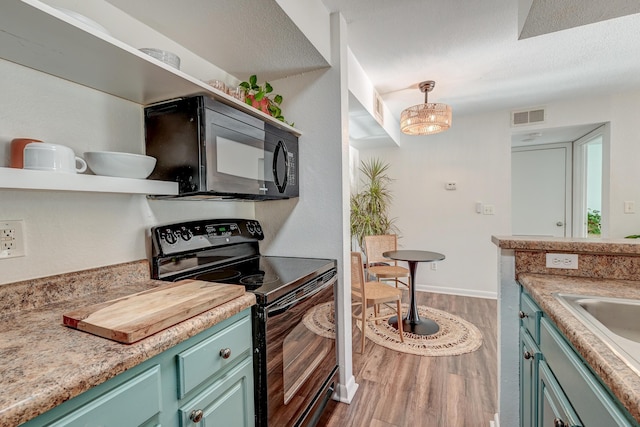 kitchen featuring black appliances, wood finished floors, visible vents, and green cabinetry